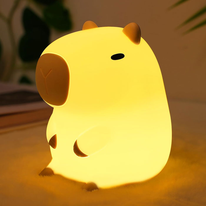 Cute capybara-shaped silicone night light glowing with a soft warm yellow light, perfect for kids' bedrooms or nurseries.