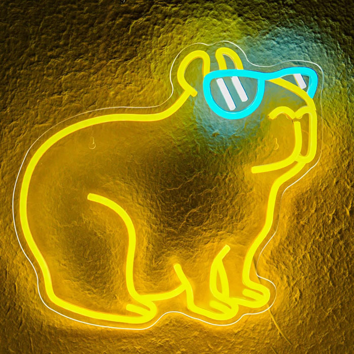 Capybara neon LED sign glowing in bright yellow with blue sunglasses, mounted on a wall, perfect for bedroom or party decoration.